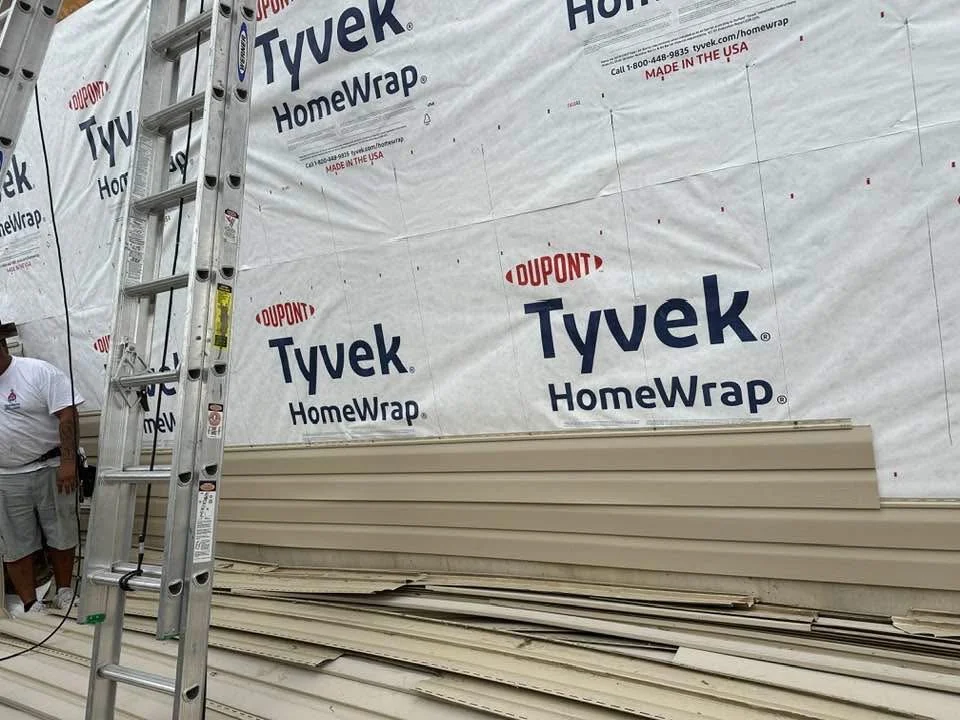 House wrap and new siding panels staged on a DLMRF exterior job site