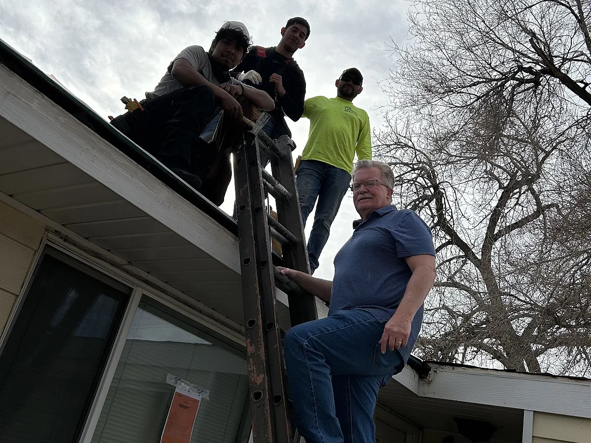 Doug Marshall and the DLMRF roofing crew on a ladder at a Littleton, Colorado home