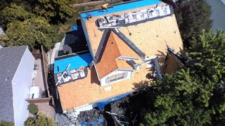 Aerial view of a home stripped to bare roof decking after shingle tear-off