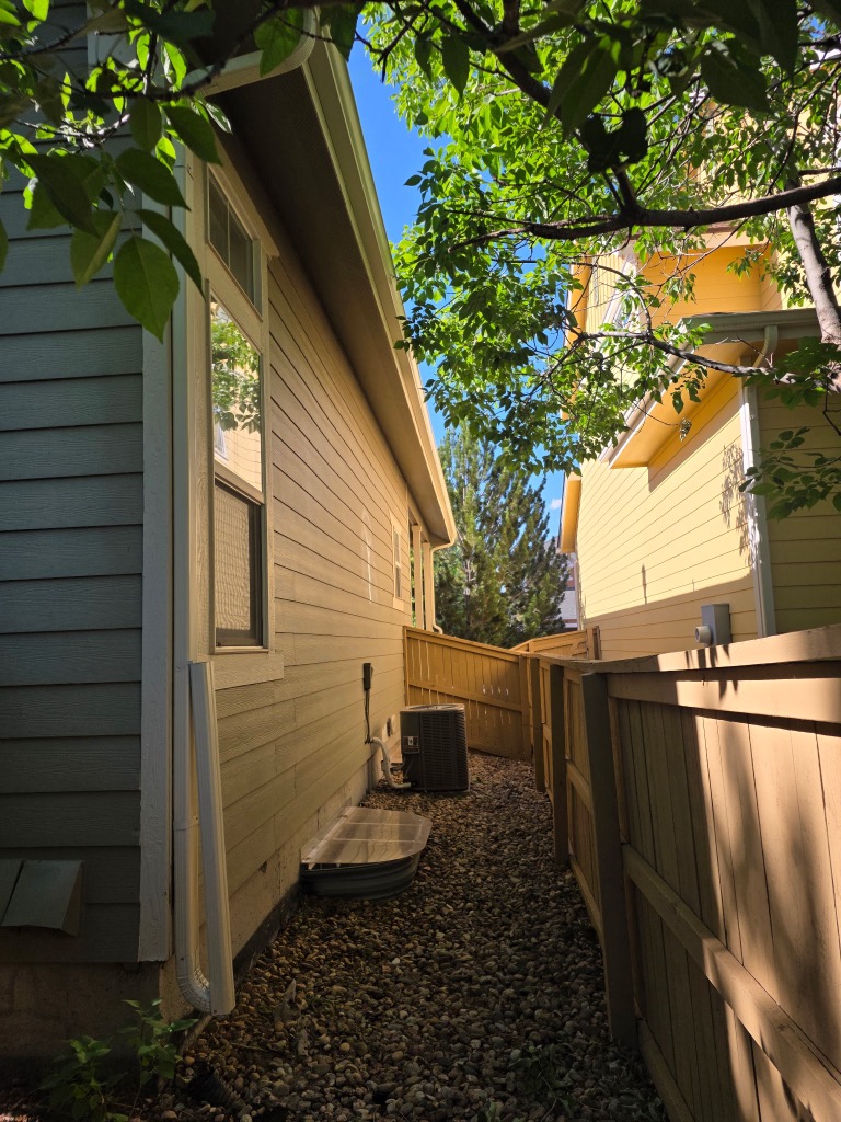 Seamless gutter and downspout running along the side of a Littleton home to a gravel drainage bed